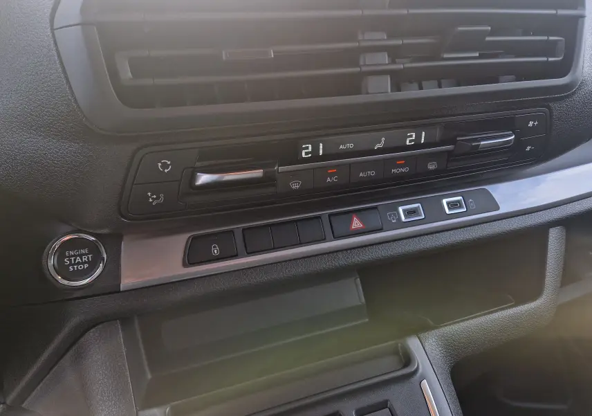 Détail du tableau de bord du Citroën Jumpy gris titane, montrant les commandes de climatisation et le bouton start/stop.