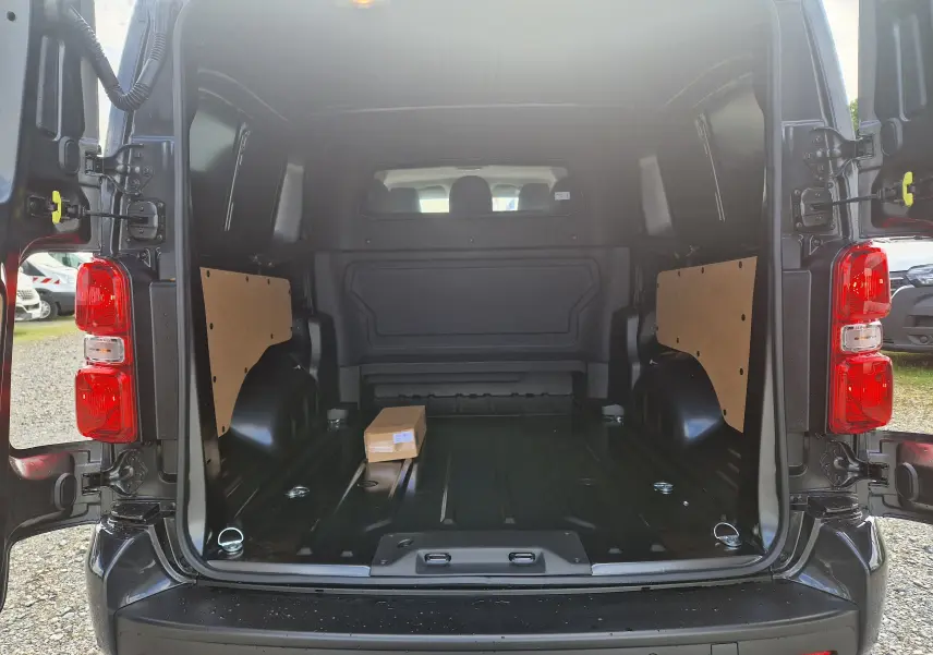 Vue arrière ouverte du Citroën Jumpy XL gris titane montrant l'espace de chargement vide avec panneaux latéraux en bois.