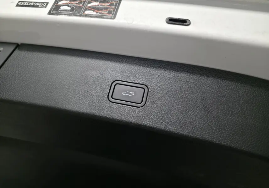 Bouton d'ouverture électrique du coffre sur la partie intérieure blanche du hayon d'une Smart #1 blanche.