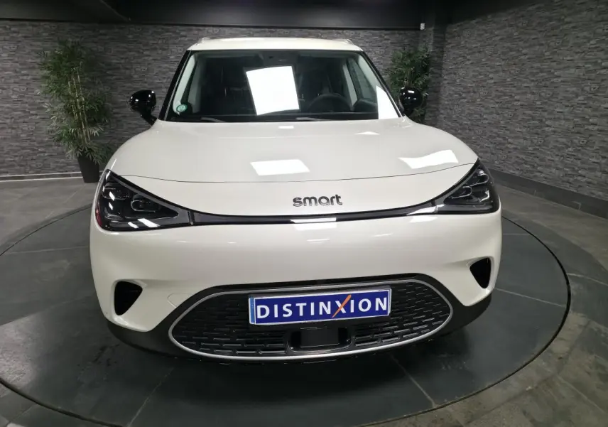 Vue de face d'une Smart #1 blanche électrique avec calandre noire et phares LED au design moderne.