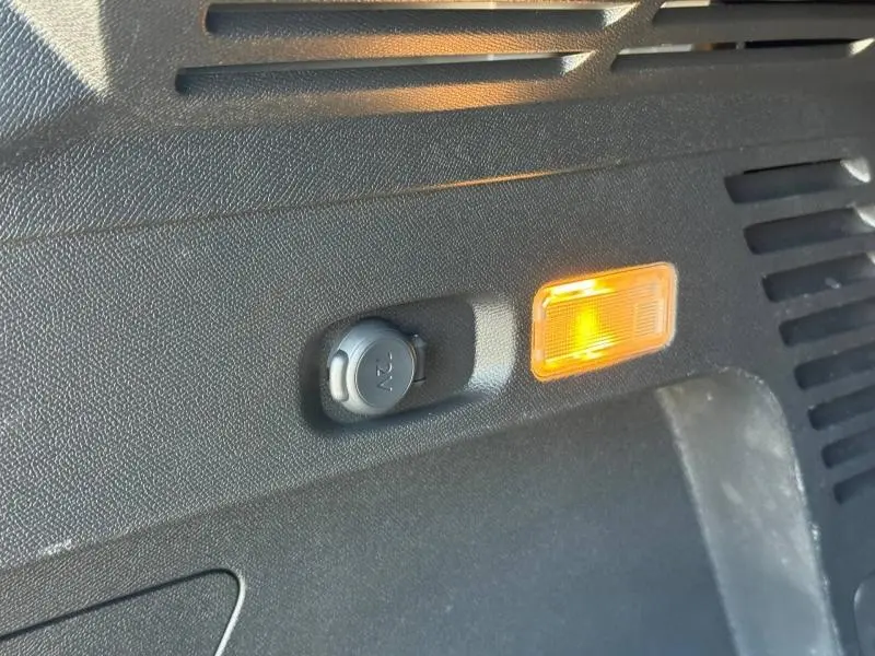 Détail intérieur du coffre du Citroën C5 Aircross gris acier montrant une prise 12V et un éclairage orange.