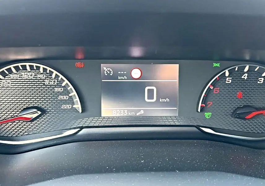 Vue rapprochée du tableau de bord numérique du Peugeot 2008 gris, affichant 0 km/h et 8233 km au compteur.
