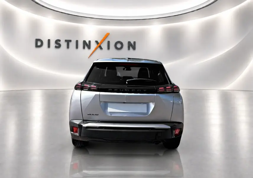 Vue arrière du Peugeot 2008 gris 2025 avec feux arrière LED et lunette arrière teintée dans un showroom lumineux.