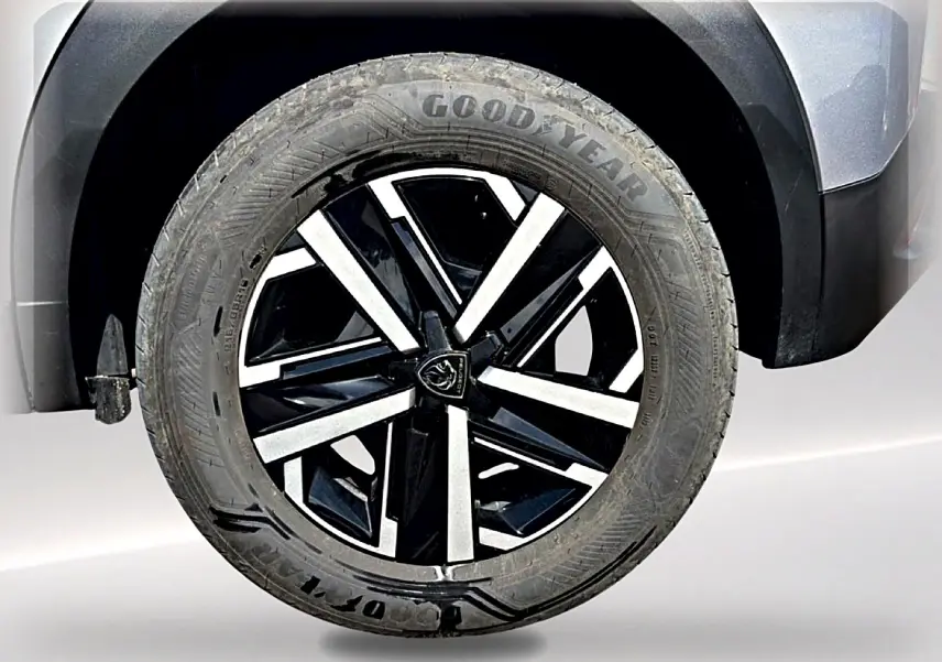 Gros plan sur la roue avant droite du Peugeot 2008 gris, avec jante noire et argentée au design moderne.
