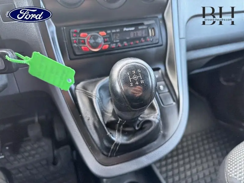 Gros plan sur le levier de vitesses manuel noir dans l’habitacle d’un Mercedes Citan blanc, avec autoradio et clé insérée.