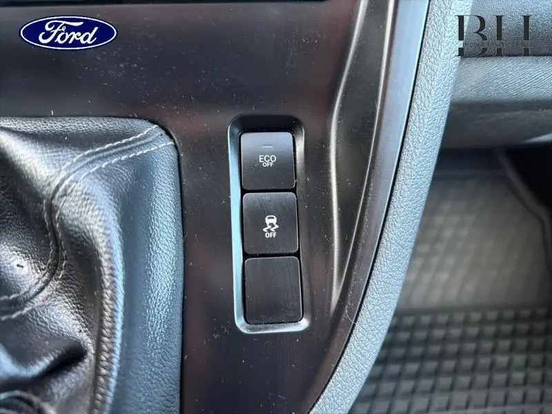 Gros plan sur les boutons de commande Eco et antipatinage désactivés, près du levier de vitesse en cuir noir.