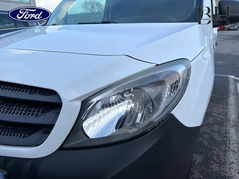 Gros plan sur le phare avant droit d’un Mercedes Citan blanc, mettant en valeur la calandre noire et le pare-chocs gris.