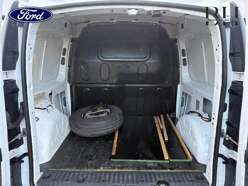 Vue arrière de l'intérieur blanc du Mercedes Citan 108 CDI Compact 2017, montrant l'espace de chargement vide avec une roue de secours.