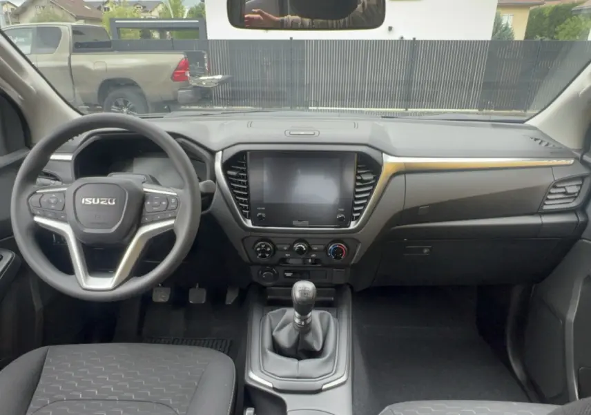 Vue intérieure frontale du tableau de bord de l'Isuzu D-MAX 2026 avec volant multifonctions et écran tactile central.