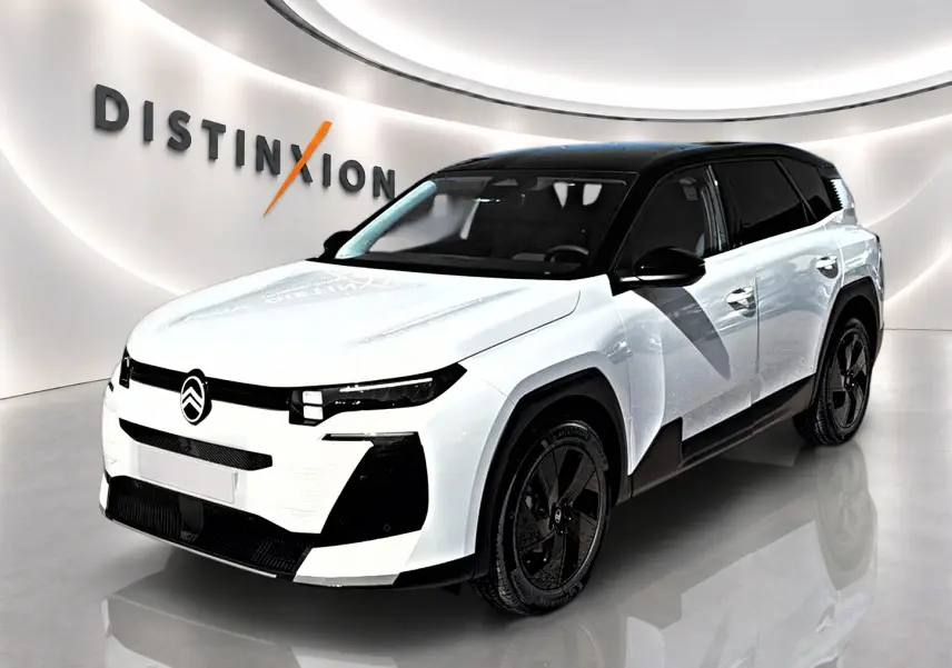 Vue 3/4 avant d'un Citroën C5 Aircross blanc à toit noir avec jantes alliage noires dans un showroom.