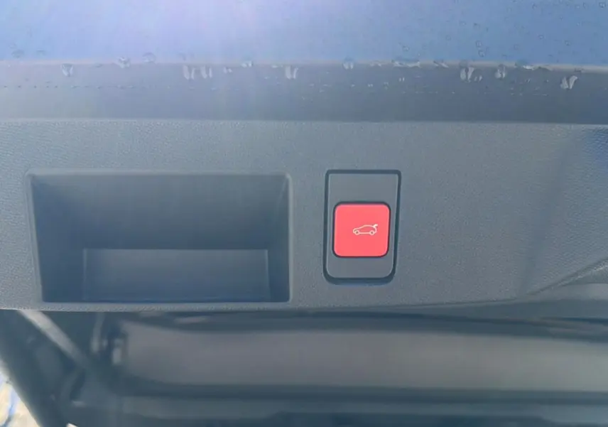 Bouton rouge d'ouverture électrique du hayon sur le bord intérieur d'un Citroën C5 Aircross blanc 2026.