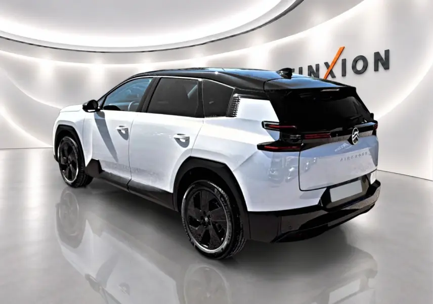 Vue 3/4 arrière droite du Citroën C5 Aircross blanc à toit noir avec jantes alliage noires dans un showroom.