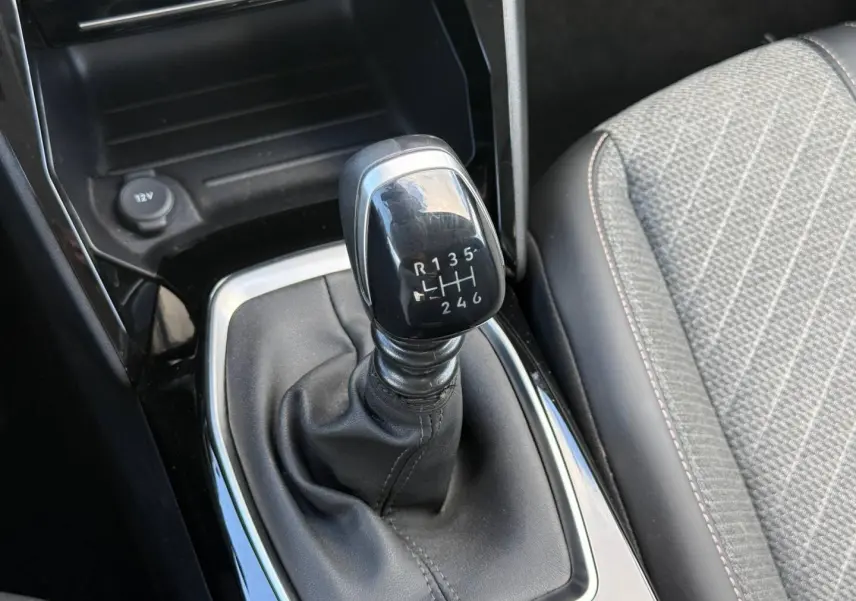 Le levier de vitesses manuel noir de la Peugeot 208 1.2 100ch Allure, avec sellerie tissu gris à motifs.