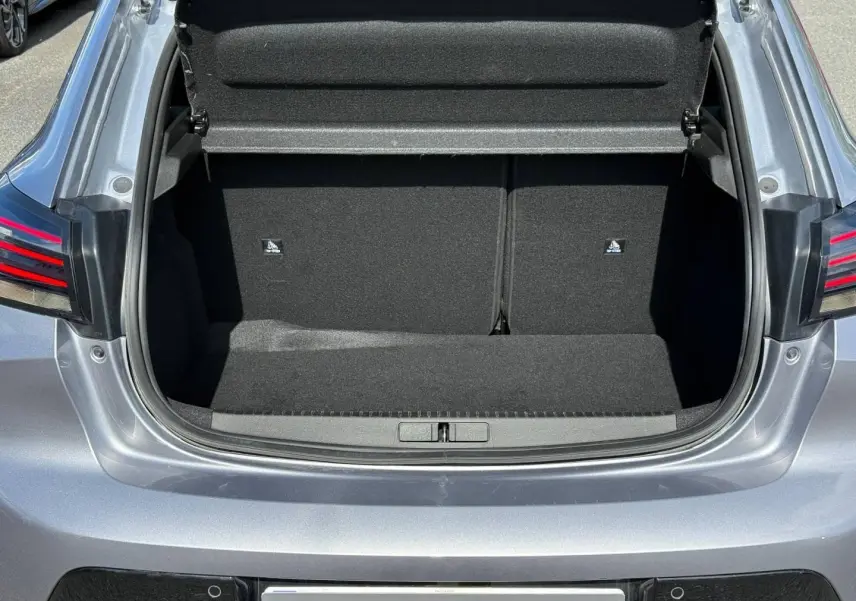 Coffre ouvert vu de l'arrière d'une Peugeot 208 gris Artense, montrant l'espace de chargement vide et les feux arrière LED.