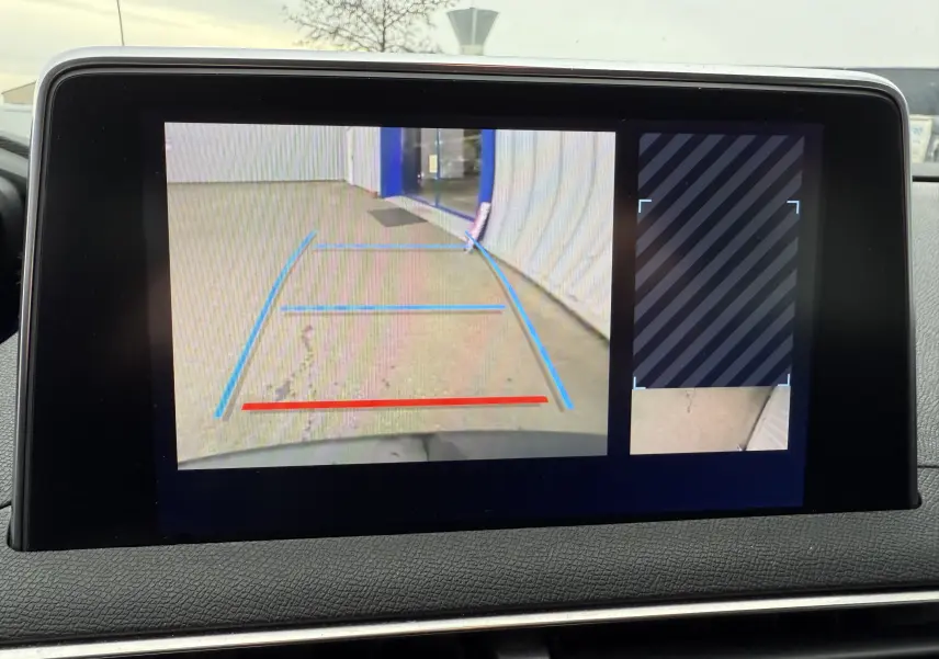 Écran intérieur du Peugeot 5008 2020 montrant la caméra de recul avec lignes de guidage colorées sur sol gris clair.