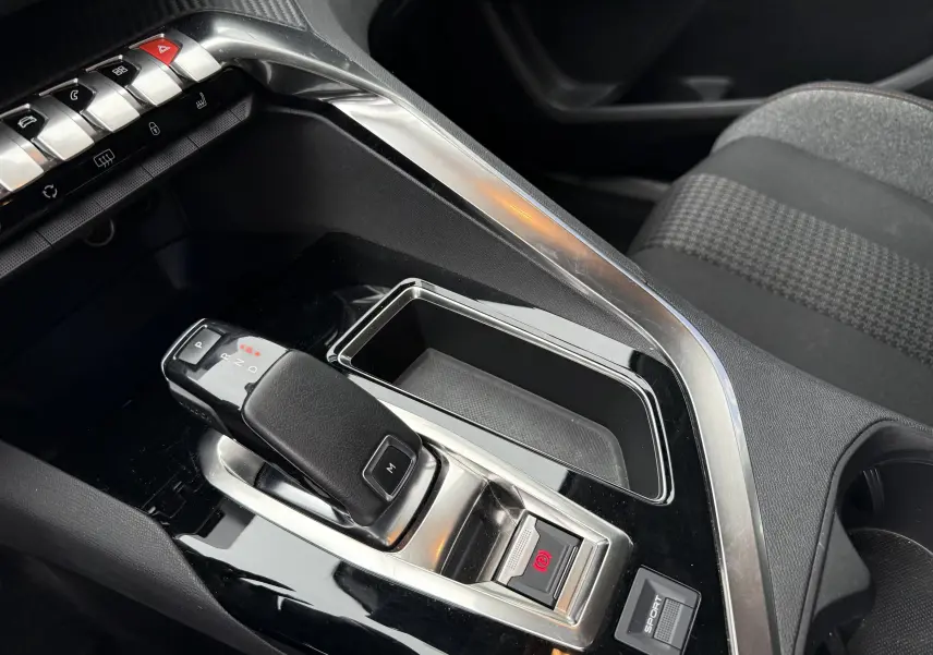 Gros plan sur la console centrale du Peugeot 5008 gris Artense, avec levier de boîte automatique et bouton sport visibles.