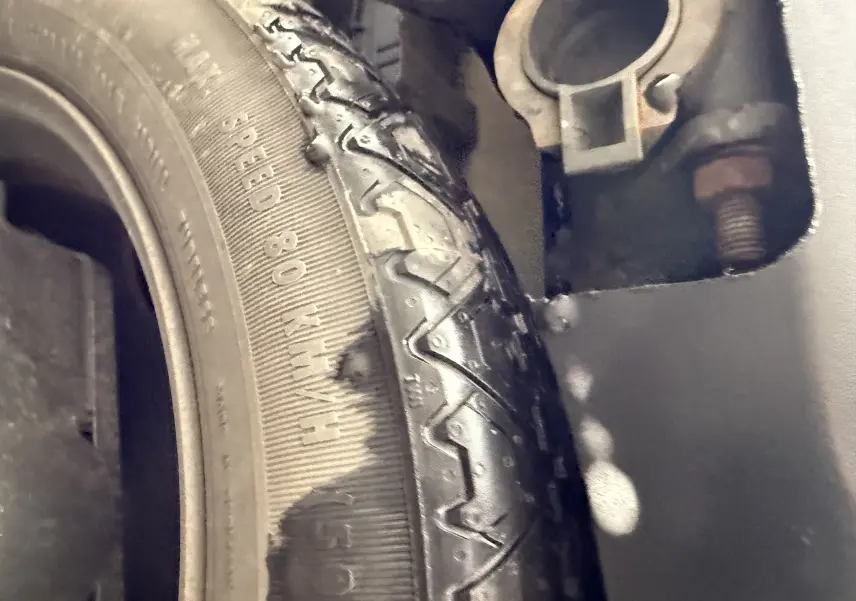 Gros plan sur un pneu usé d'un Peugeot 5008 gris Artense, montrant les détails de la bande de roulement et le flanc.