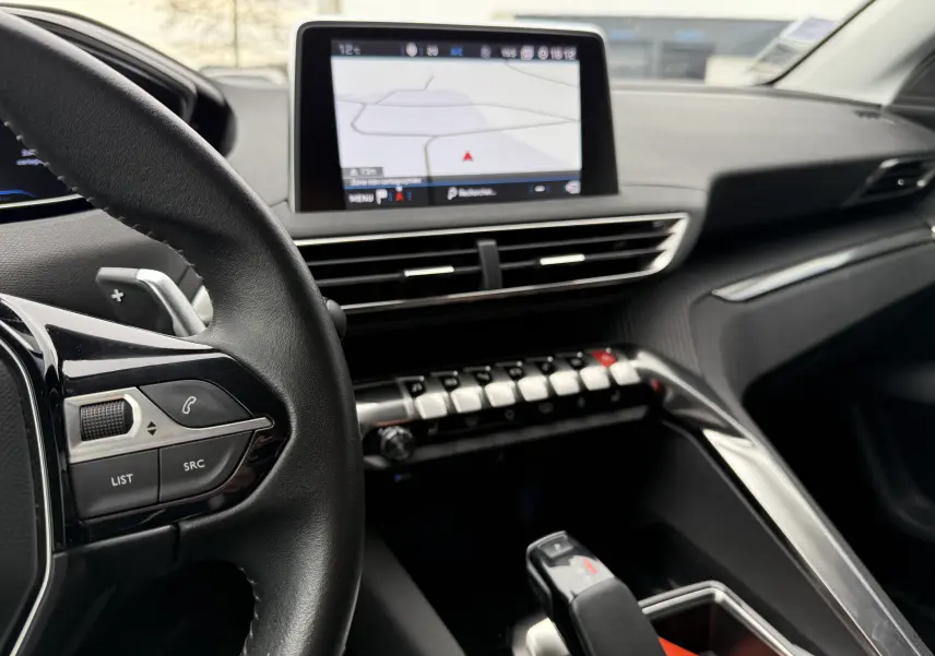 Vue intérieure centrée sur le tableau de bord et la console centrale du Peugeot 5008 2020 avec écran tactile et volant noir.