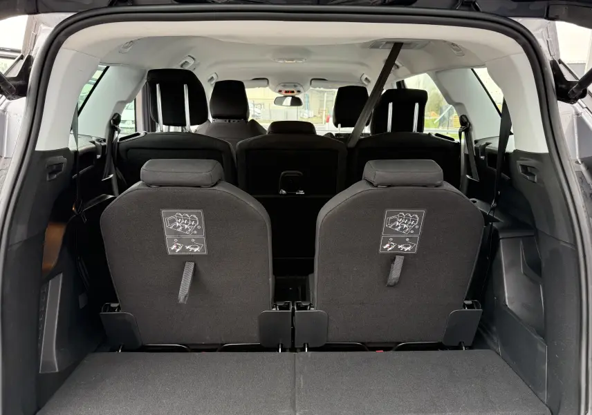 Vue arrière intérieure du Peugeot 5008 gris Artense montrant les sièges rabattables de la troisième rangée et l'habitacle spacieux.