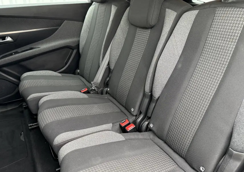 Vue latérale des sièges arrière gris foncé et clair du Peugeot 5008, mettant en valeur les ceintures de sécurité et les textures du tissu.