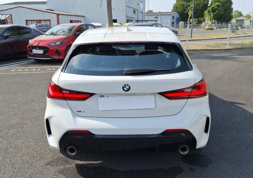 Vue arrière d'une BMW Série 1 blanche 120i M Sport 2021 avec feux rouges allumés et double sortie d'échappement chromée.