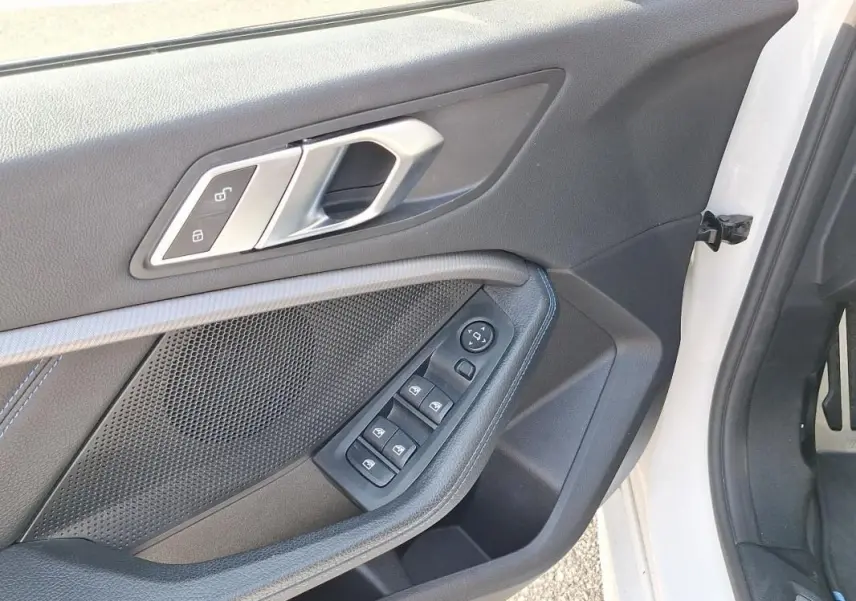 Gros plan sur la porte avant gauche blanche d'une BMW Série 1 120i M Sport, avec commandes électriques et poignée argentée.