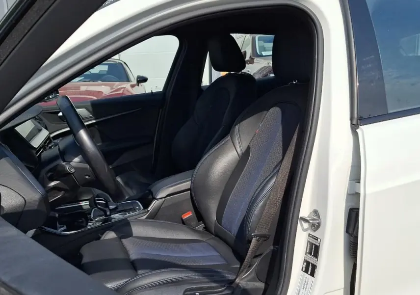 Intérieur côté conducteur d'une BMW Série 1 blanche 120i M Sport 2021, sièges sport cuir noir et bleu.