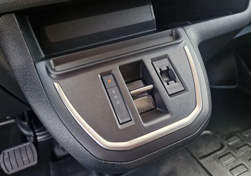 Gros plan sur la console centrale du Citroën Jumpy XL gris titane, montrant la commande de boîte auto et prise 12V.