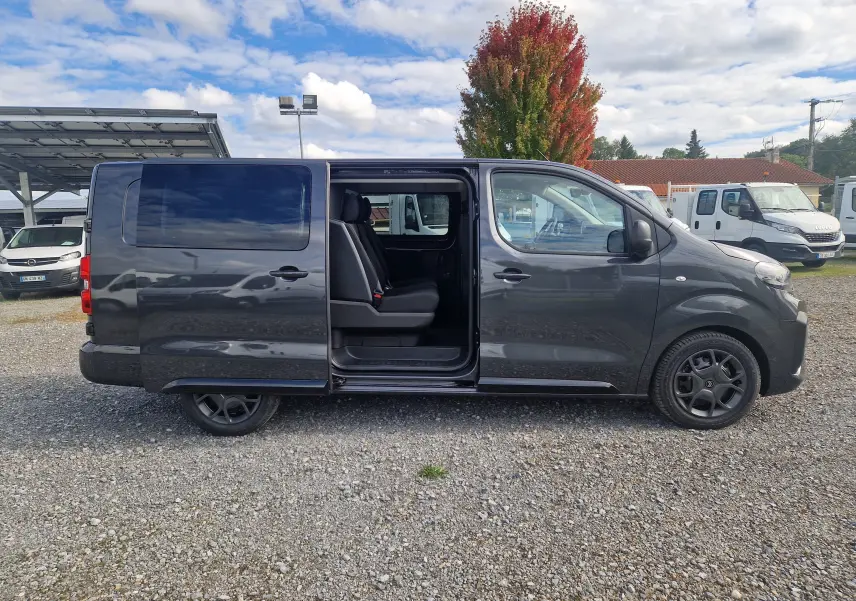 Profil droit d'un Citroën Jumpy cabine approfondie gris titane avec porte coulissante ouverte et sièges visibles.