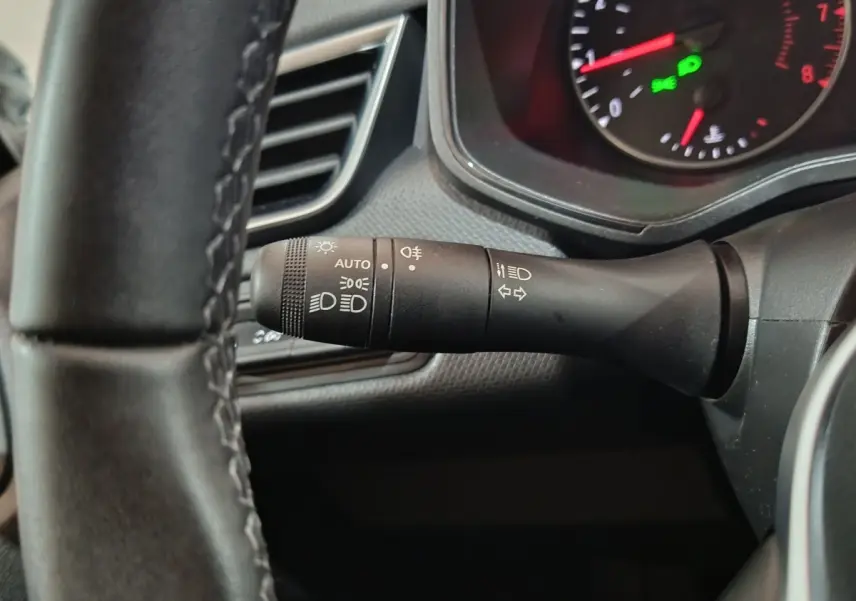 Gros plan sur la manette de commande des phares et clignotants à gauche du volant cuir d'une Renault Clio gris clair 2023.