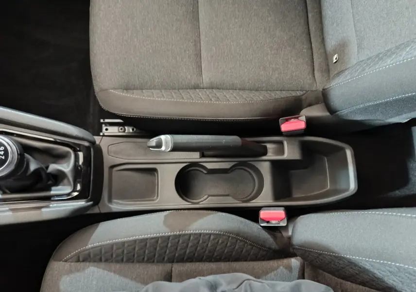 Vue plongeante sur la console centrale grise de la Renault Clio 2023, avec frein à main manuel et sièges tissu gris.