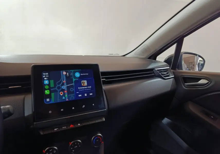 Vue intérieure côté passager de la Renault Clio gris clair 2023, avec écran tactile central affichant navigation et musique.