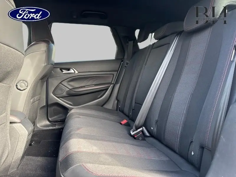 Vue intérieure côté droit des sièges arrière en tissu noir avec surpiqûres rouges, banquette 3 places, ceintures visibles.