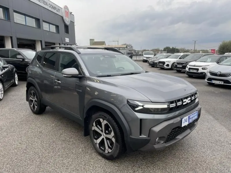 Vue 3/4 avant droite du Dacia Duster 1.6 Hybrid 140 cv gris schiste 2025 avec jantes distinctives et calandre moderne.