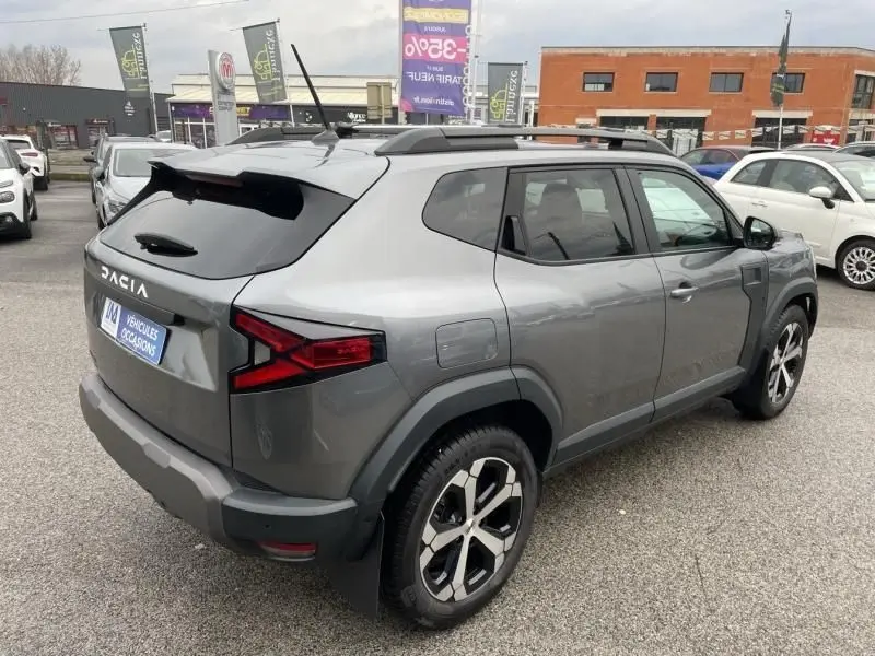 Vue 3/4 arrière droite du Dacia Duster 1.6 Hybrid 140 cv gris schiste, avec jantes alliage et toit noir contrasté.