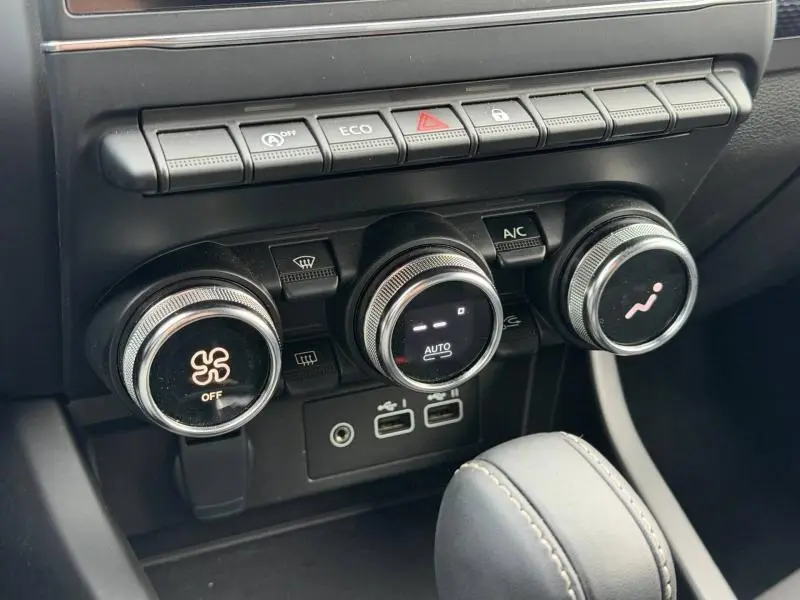 Gros plan sur les commandes de climatisation et les boutons de fonction du tableau de bord du Renault Arkana blanc 2025.