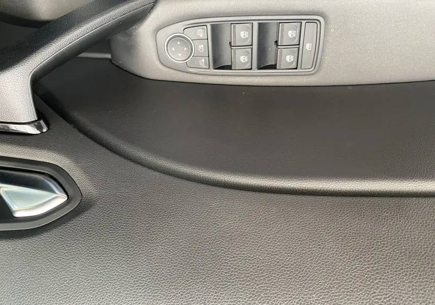 Panneau de porte côté gauche du Mitsubishi ASX 2023 avec commandes des vitres électriques et poignée intérieure noire.