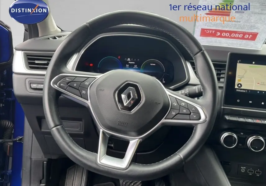 Vue intérieure centrée sur le volant noir de la Renault Captur bleu iron metal, avec tableau de bord numérique et écran tactile.