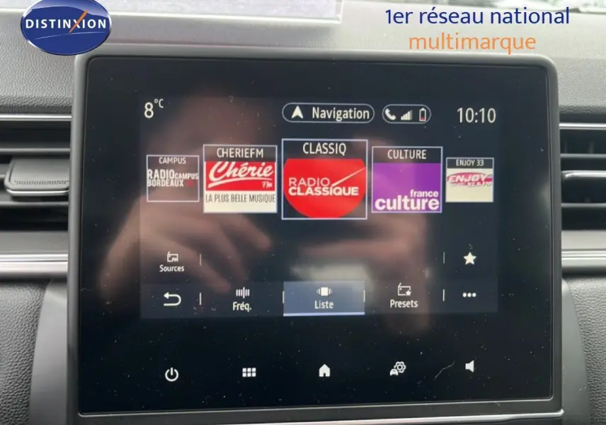 Vue rapprochée de l’écran tactile multimédia du Renault Captur 1.6 E-TECH bleu iron métal avec toit noir, affichant les radios.