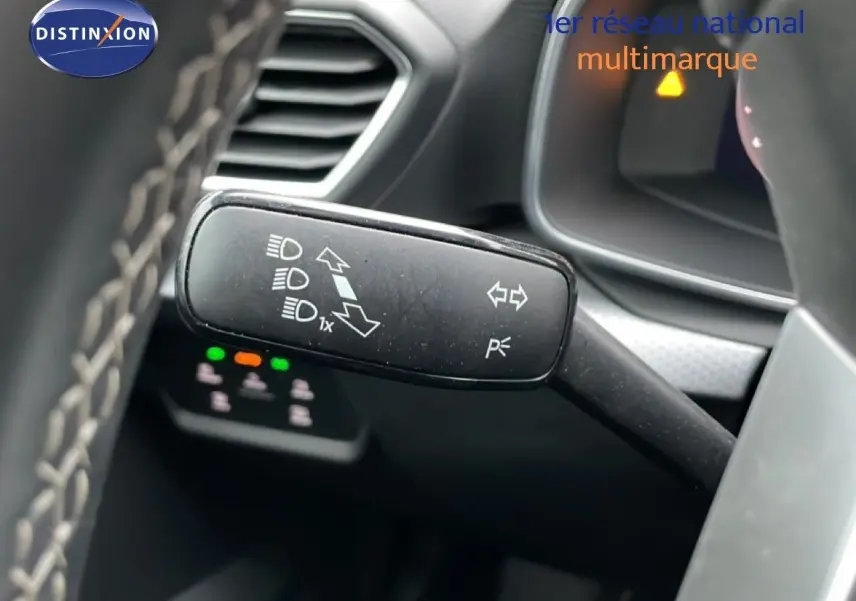 Gros plan sur la commande des clignotants et feux du SEAT LEON ST bleu Fjord, intérieur gris noir visible en arrière-plan.