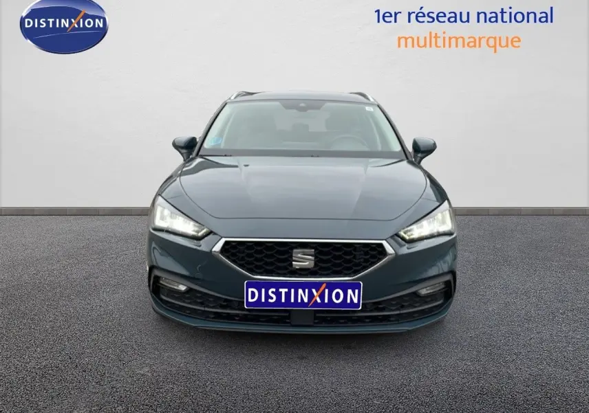 Vue avant frontale d'une SEAT LEON ST IV 1.5 TSI bleu fjord avec calandre hexagonale et phares LED allumés.