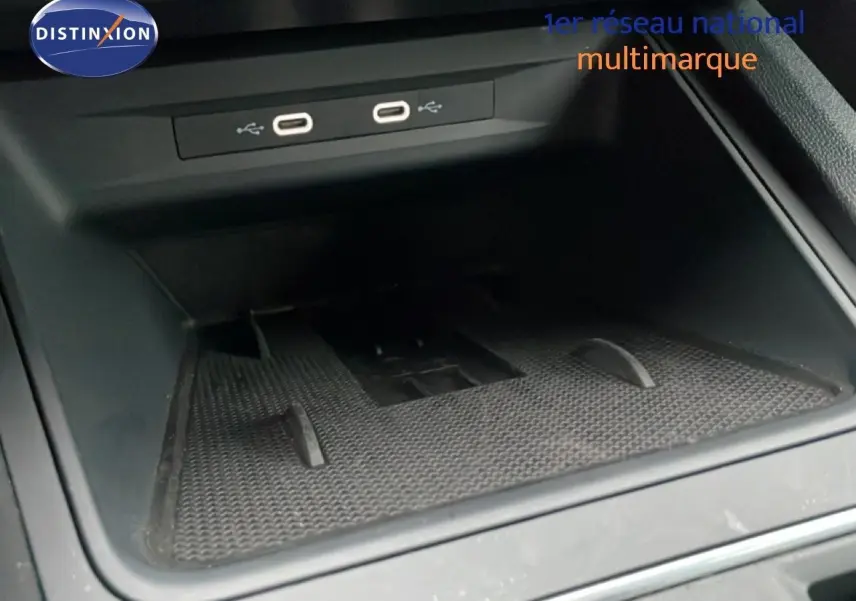 Gros plan sur le compartiment de rangement intérieur avec deux ports USB visibles dans une SEAT Leon ST bleu Fjord.