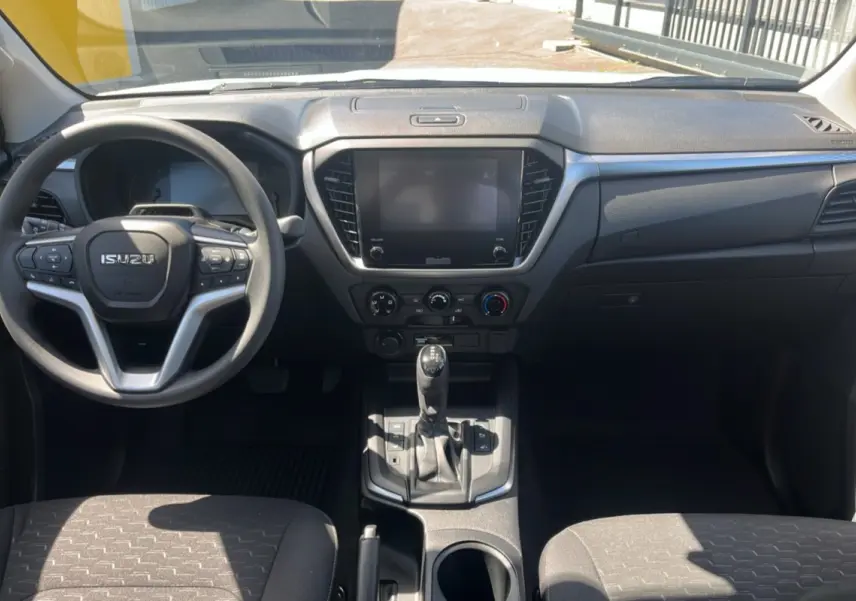 Vue intérieure avant de l'Isuzu D-MAX 2026 avec tableau de bord noir et volant multifonctions.