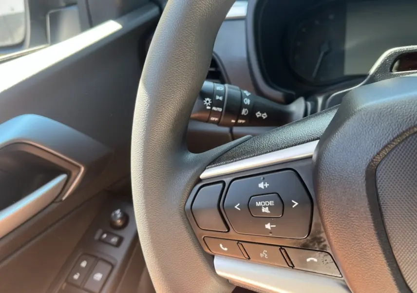 Gros plan sur le volant multifonctions noir de l'Isuzu D-MAX 2026, avec commandes audio et téléphone côté gauche.