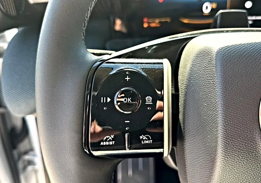 Gros plan sur les commandes multifonctions noires à gauche du volant du Citroën C5 Aircross hybride 2026.