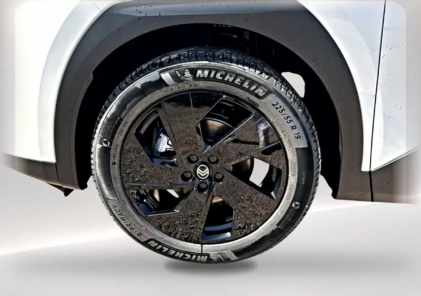 Gros plan sur la roue avant droite noire et jante alliage 19 pouces du Citroën C5 Aircross blanc et noir.