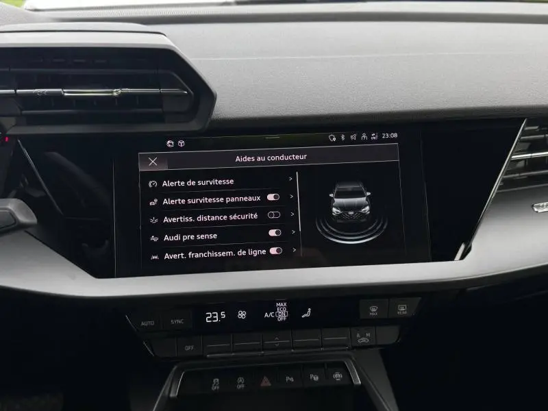 Vue rapprochée de l'écran tactile central affichant les aides à la conduite dans l'Audi A3 Sportback blanche 2024.