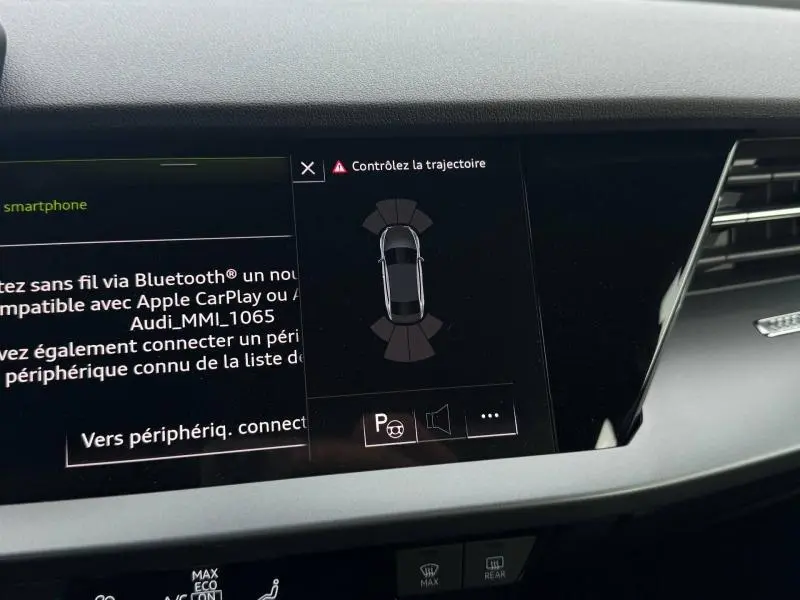 Écran central de l’Audi A3 Sportback 2024 montrant l’aide au stationnement avec vue du véhicule en gris sur fond noir.