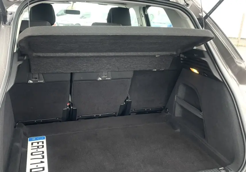 Coffre ouvert vu de l'arrière d'une Citroën C4 Picasso marron, avec cache-bagages relevé et banquette arrière visible.