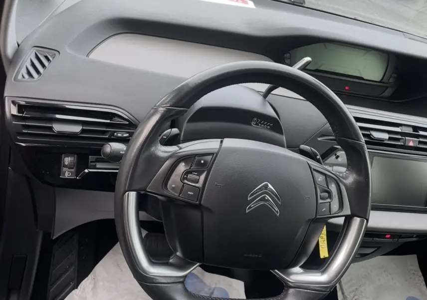 Vue intérieure centrée sur le volant cuir multifonction d'une Citroën C4 Picasso 2017, tableau de bord et écran tactile visibles.